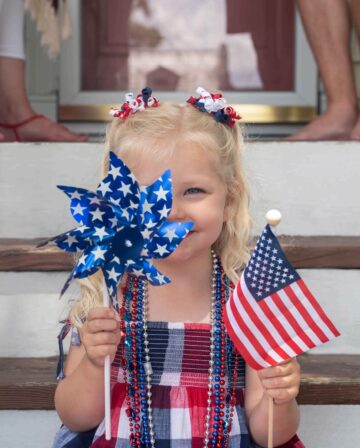 portrait smiling girl holding american flag steps